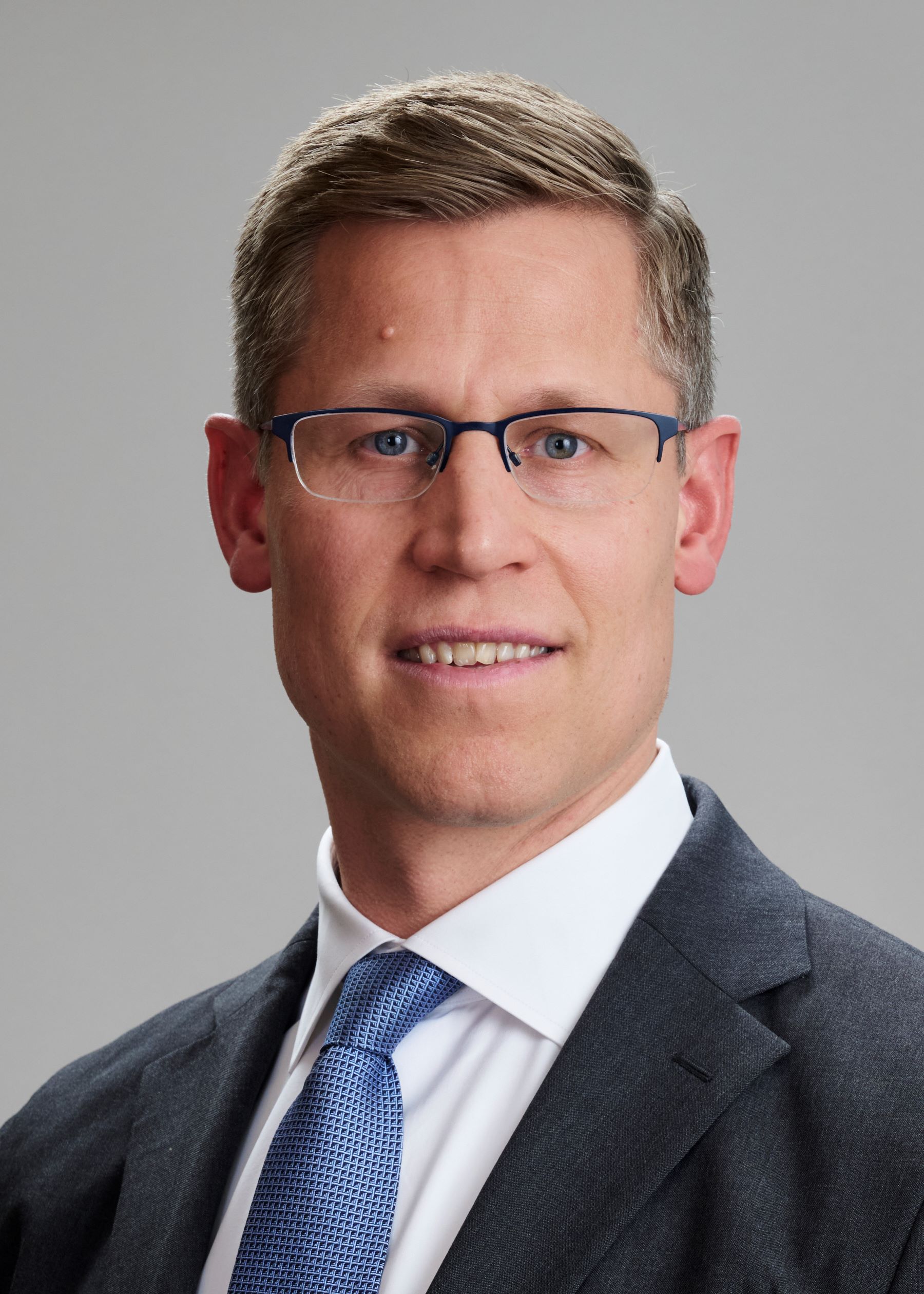 Laust Helmig wears a suit against a grey background. 