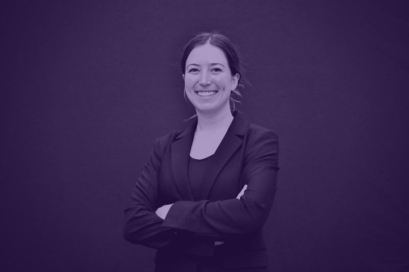 a woman in a suit smiles with arms crossed