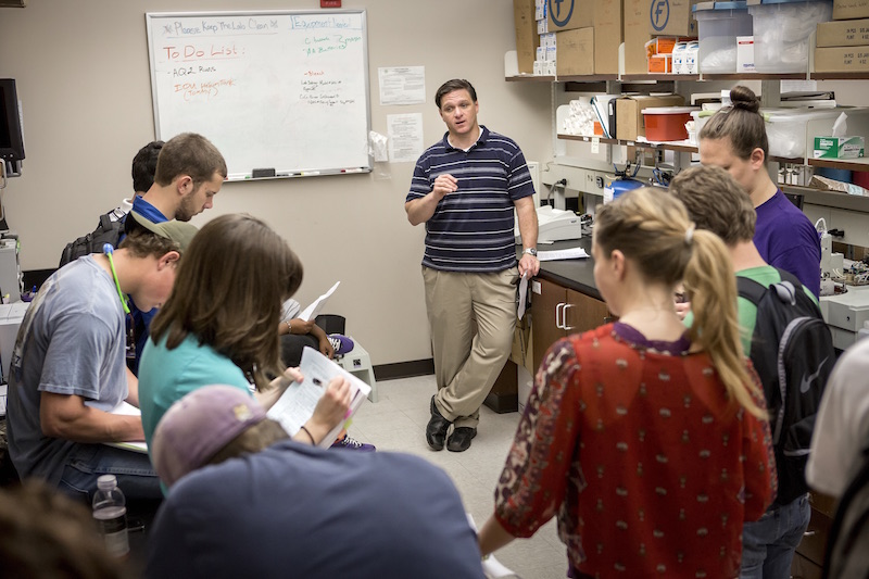 a professor lectures to a class in a lab