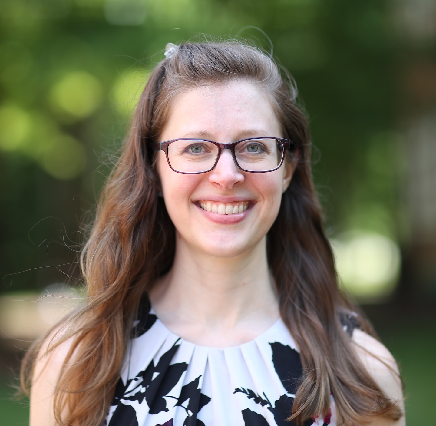Professional headshot of Dr. Renée Altergott smiling at the camera in front of a blurred natural background