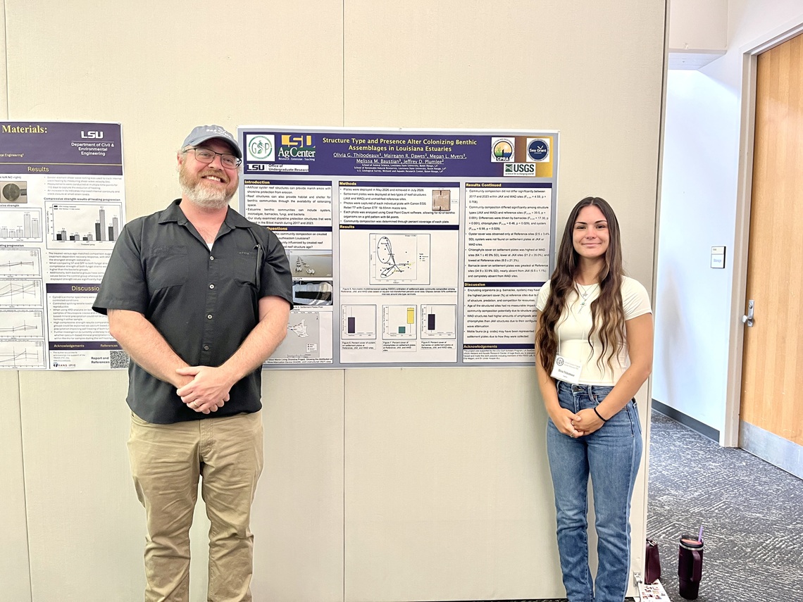 Student and faculty mentor stand next to research poster during presentation event.